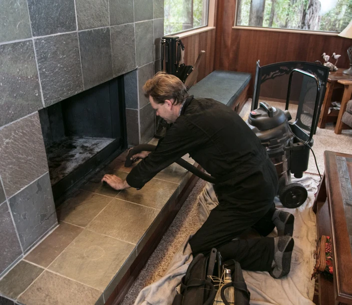 Technician cleaning a chimney in a residential home.