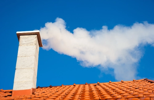 Chimney venting clean, white smoke into a clear blue sky, suggesting proper ventilation.