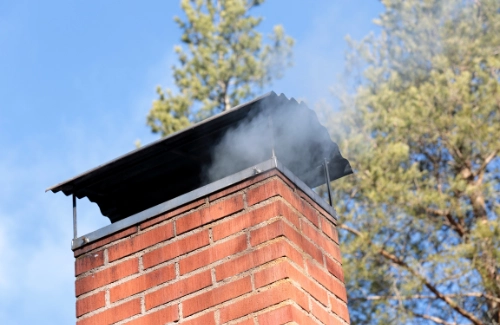 Chimney with light smoke rising from the flue, indicating a properly functioning ventilation system.