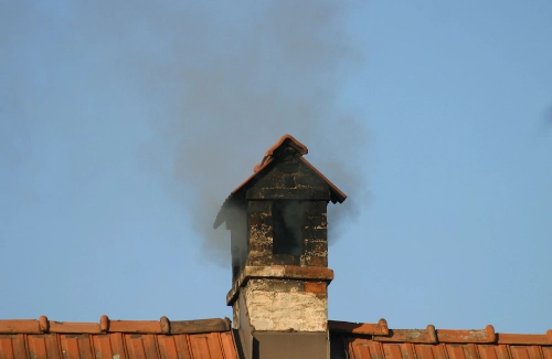 Chimney emitting thick, black smoke, indicating a blockage or malfunction.
