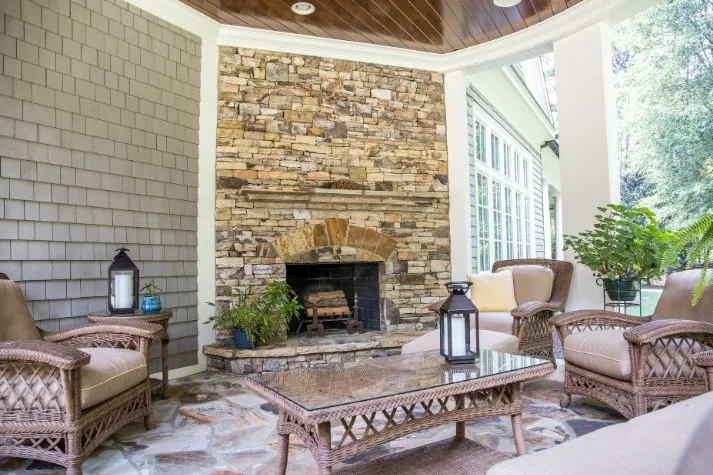 Stone fireplace in a cozy outdoor living space with seating and natural light.