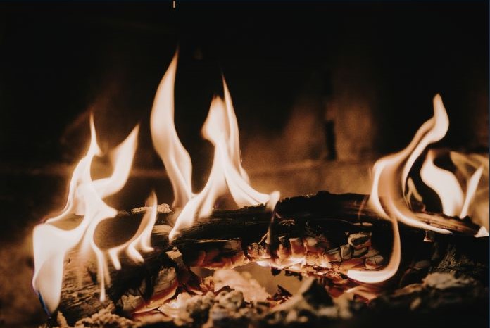 Close-up view of a burning log in a fireplace with flames dancing.