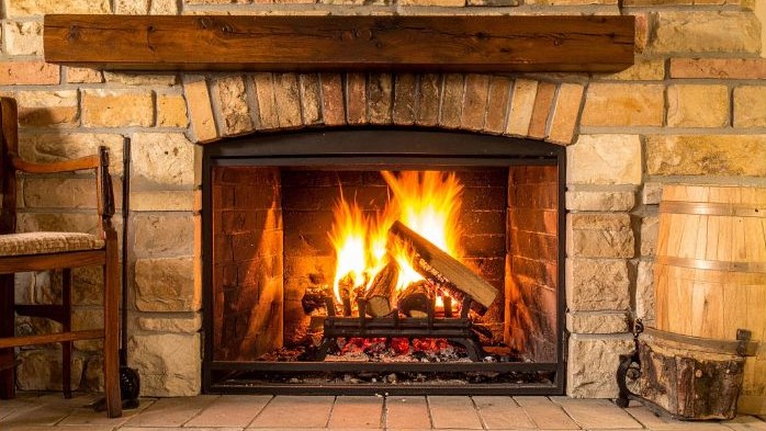 Traditional fireplace with a wooden mantel, brick arch, and glowing fire.